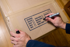 Mover carefully labeling boxes while preparing small shipments in Massachusetts