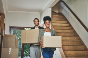 smiling couple holding boxes in new home after learning how to move to another state
