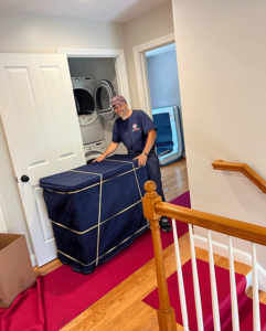 local moving services provider smiling while carefully hauling large items through home